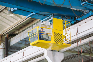 The girl working in the cab of a crane. Heavy industry, metal factory.