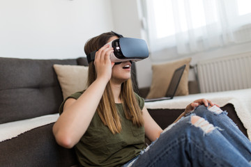 Beautiful young woman enjoying virtual reality at her home.