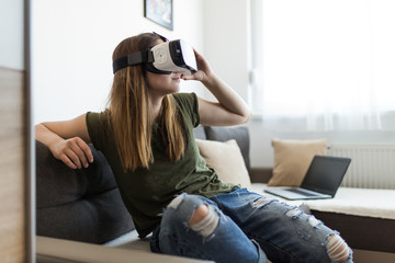 Beautiful young woman enjoying virtual reality at her home.