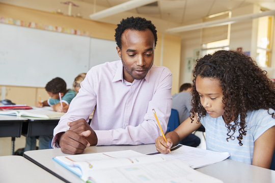 Elementary school teacher working with schoolgirl, close up
