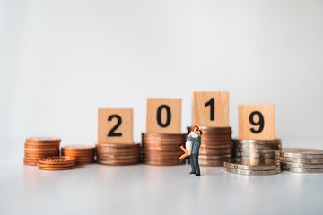 Miniature people, happy man and woman standing wooden block year 2019 and stack coins  using as businss and family concept