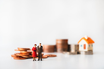 Miniature people,husband and wife standing with mini house and stack coins using as business, family and property concept