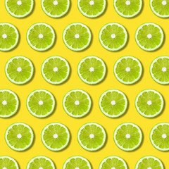 Green lime slices pattern on vibrant yellow color background. Minimal flat lay food texture 