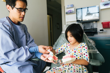 Dentist teaches young girl proper tooth brushing technique