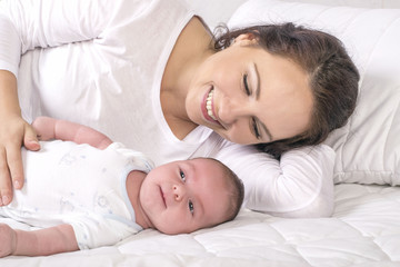 Fototapeta na wymiar Mother and baby on a white bed