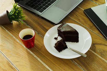 Delicious chocolate cake with hot coffee drink on wood table office for Life technology concept