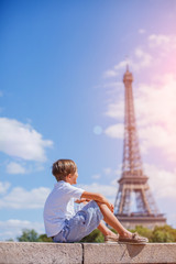 Fototapeta na wymiar Boy sitting and watching down near the Eiffel tower