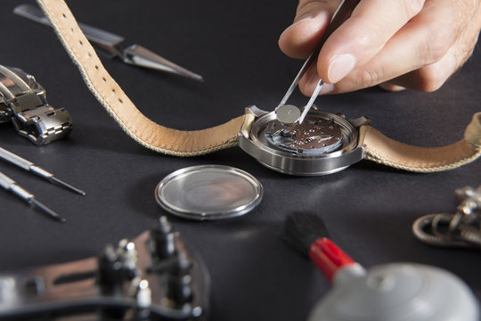 Detail of the work of a watchmaker who replaces a battery / Close up of replacing a watch battery with watchmaker tools
