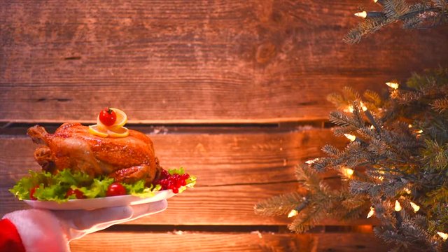 Christmas Holiday dinner. Santa's hand holding roasted chicken. Slow motion. 4K UHD video 3840X2160