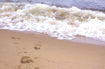 Fototapeta na wymiar steps on the sand on the beach, going to the wave