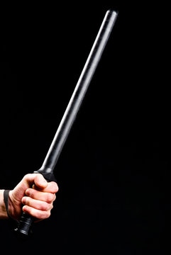 Police Truncheon in hand on black background.