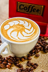 Retro manual Coffee gringer on the table with cup of coffee.