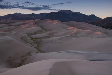 Fotobehang Vast landscape of dunes topped with rosy sunset light in Great Sand Dunes National Park, backed by the Rocky Mountains © Jim Ekstrand