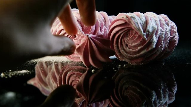 human hand sets small pink marshmallow near three handmade zephyrus