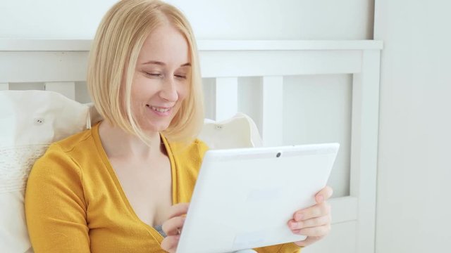 Attractive blonde European woman smiling and using digital tablet pc.