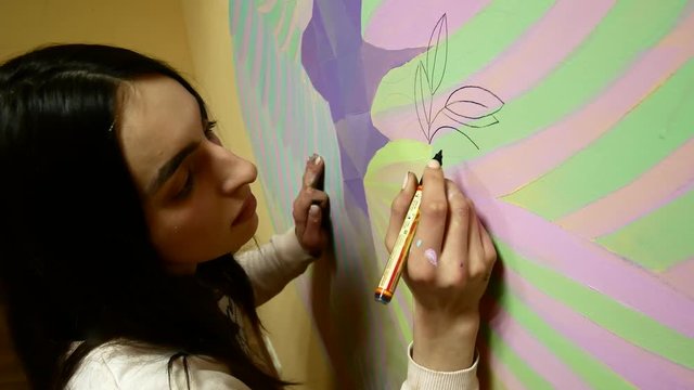 Young brunette paints a picture on the wall, profile