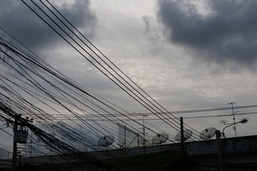 Silhouette of electricity cables and satellite dishes 