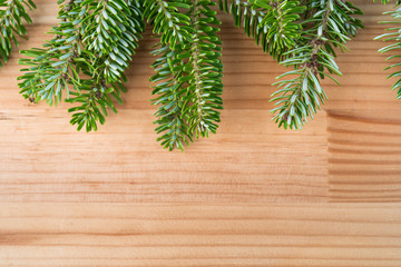 Green fresh Christmas tree pine branches on natural wooden background. Copy space on the bottom.