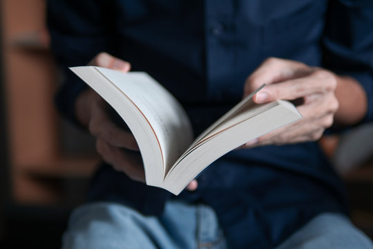 Man in blue shirt reading a book - Powered by Adobe