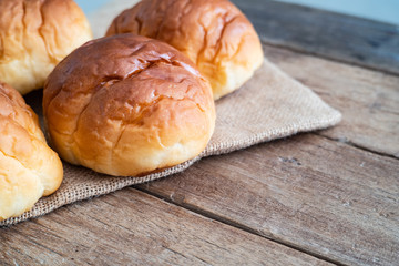 fresh butter roll bread bun on gunny sack cloth on wooden table, close up