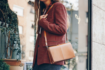 street style, attractive woman wearing a  mini skirt, check plaid blazer and a lether brown tote...