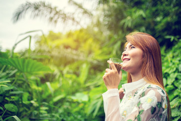 Young asian woman drinking a cup of coffee and enjoy nature view in morning.