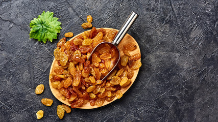 Yellow big raisins on black concrete background with copy space. Top view of dried grapes.