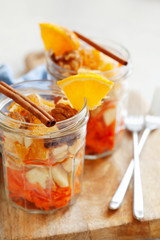 Concept of vitamin healthy salad with carrot, apples, orange, mixed nuts garnished with olive oil and cinnamon. Take away diet snack