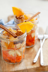 Concept of vitamin healthy salad with carrot, apples, orange, mixed nuts garnished with olive oil and cinnamon. Take away diet snack