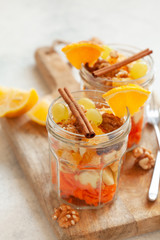 Concept of vitamin healthy salad with carrot, apples, orange, mixed nuts garnished with olive oil and cinnamon. Take away diet snack