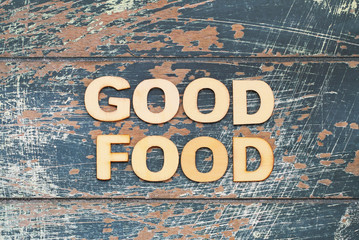 Good food written with wooden letters on rustic blue surface
