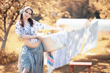 Naklejka premium Pregnant woman hanging sheets on the rope for drying