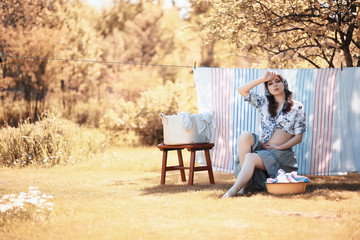 Pregnant woman hanging sheets on the rope for drying