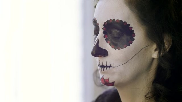 Halloween face art. Make-up artist is making woman up as skeleton for celebration of the Mexican Day of the Dead. 4K