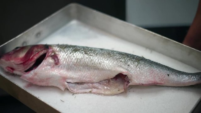 Prepating a fish to bake in salt and herbs