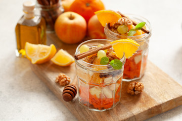 Concept of vitamin healthy salad with carrot, apples, orange, mixed nuts garnished with olive oil and cinnamon. Take away diet snack