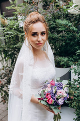 A bride in a white dress is holding a beautiful wedding bouquet.