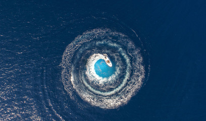 Luftaufnahme über ein Im Kreis fahrendes Boot, was runde Schaumwellen produziert