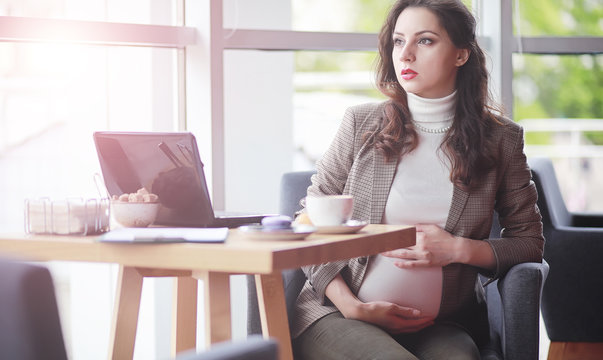 Pregnant Woman Working On Computer In Cafe