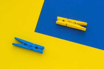 Blue and yellow clothespins on the background