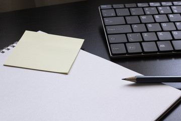 Notepad with a pencil on the table next to the keyboard