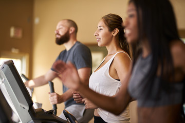 three people using treadmills in gym together