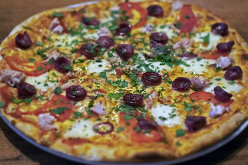 appetizing pizza with slices of sausages, cheese, tomatoes and greens