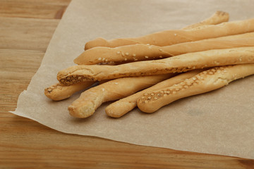 Bread sticks lie on paper on a wooden background