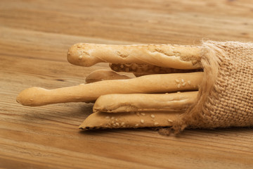 Bread sticks wrapped in burlap on a wooden background