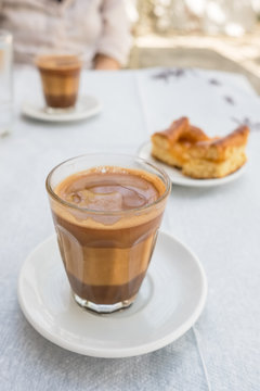 Traditional greek coffee served with a piece of pie in outdoor cafe in Greece