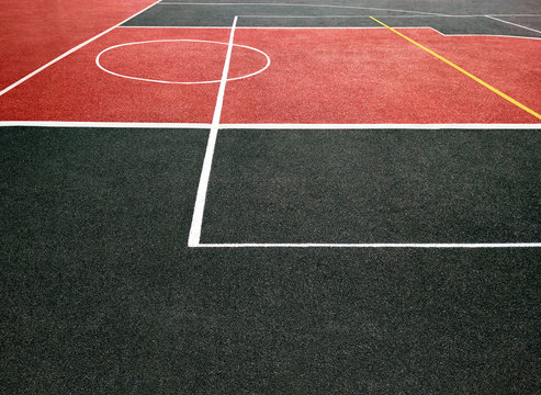 Surface of red and black sports field with white lines. Playing ground for games