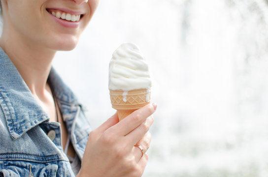 Close-up of a young woman with an ice cream cone sitting near the fountain