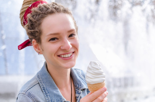 Young woman in a denim jacket with an ice cream cone sitting near the fountain in Kiev