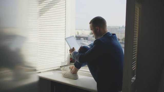 Male businessman studying economic picture sitting on windowsill